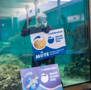 Scuba diver holds up a sign underwater.